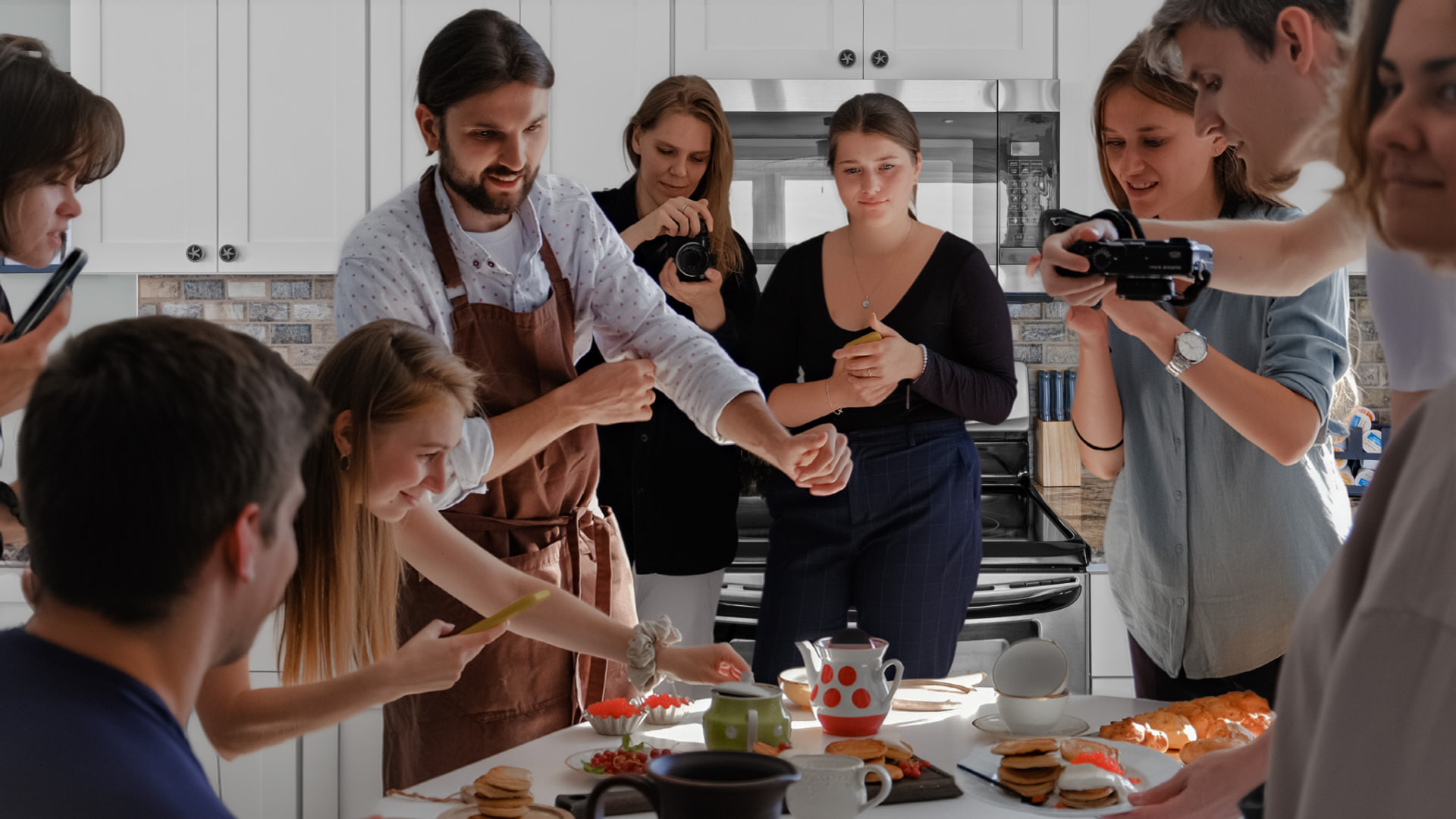 A chef and guests gathered around a kitchen island during a private cooking session