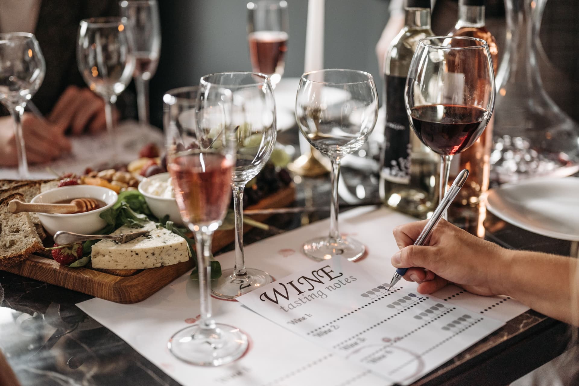 Wine glasses, a cheese board, and tasting notes on a candlelit table