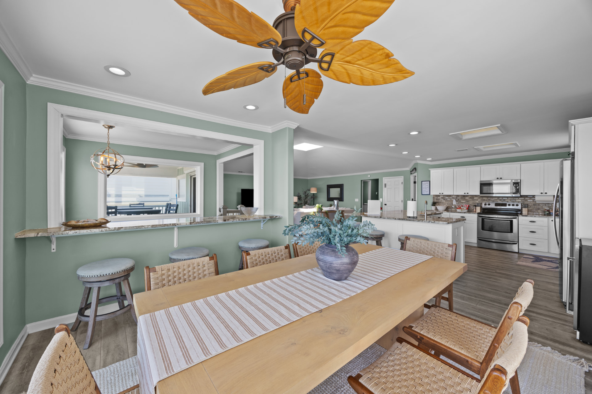 The long dining table running toward the kitchen and bar seating beyond