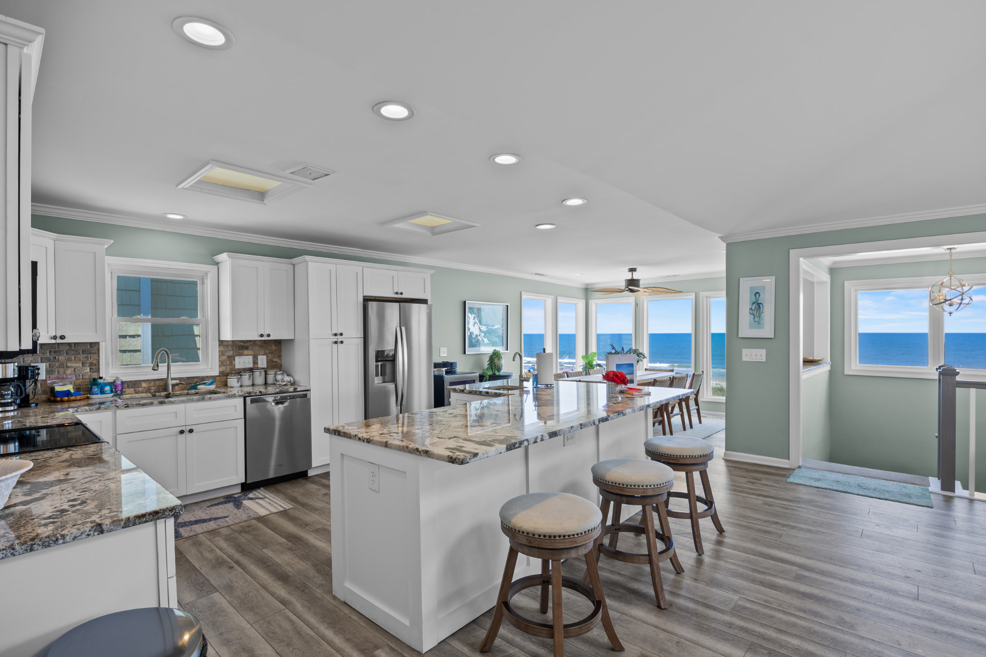 The kitchen island and bar stools with the ocean filling the windows beyond