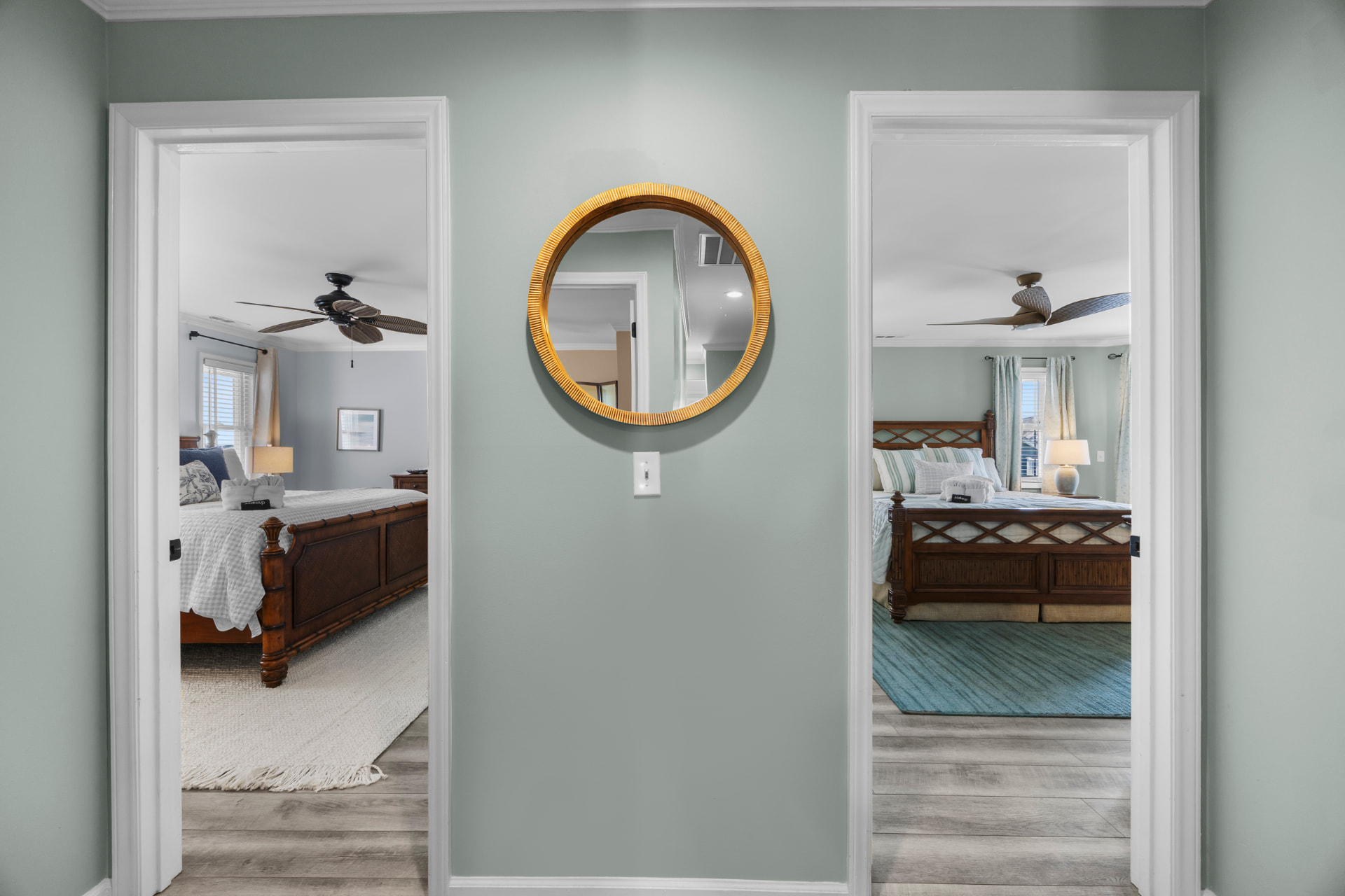 Two bedroom doorways open off the hall, a round mirror centered between them